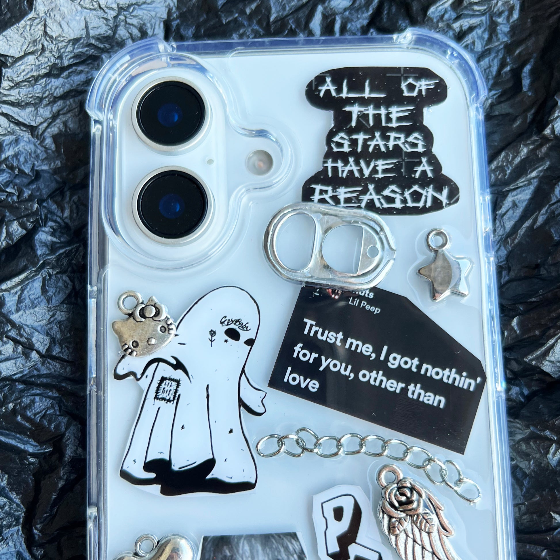 Close-up detail of the handmade Lil Peep phone case, showing the 3D texture of silver metal charms, chains, a miniature soda tab, and glossy resin-sealed goth collage elements